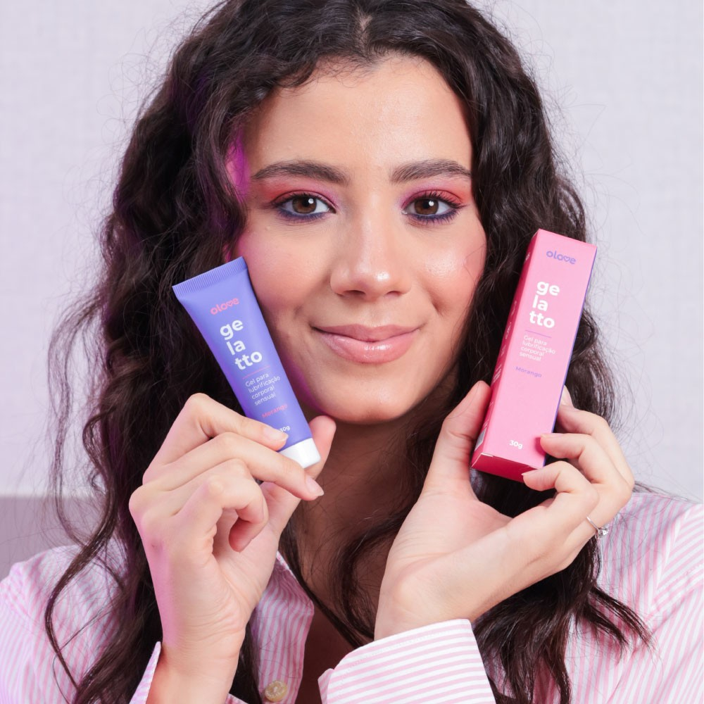 Mulher segurando o Gel Lubrificante Beij�vel Ice Gelatto Sabor Morango e sua embalagem, sorrindo para a c�mera