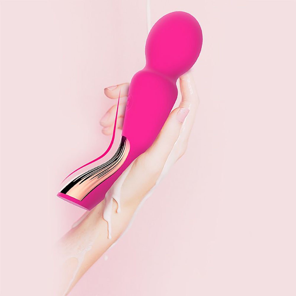 Massageador Wand Varinha M�gica com 7 Vibra��es em Silicone Recarreg�vel Pink em uma mao, com liquido branco escorrendo, realcando o material macio e resistente a agua