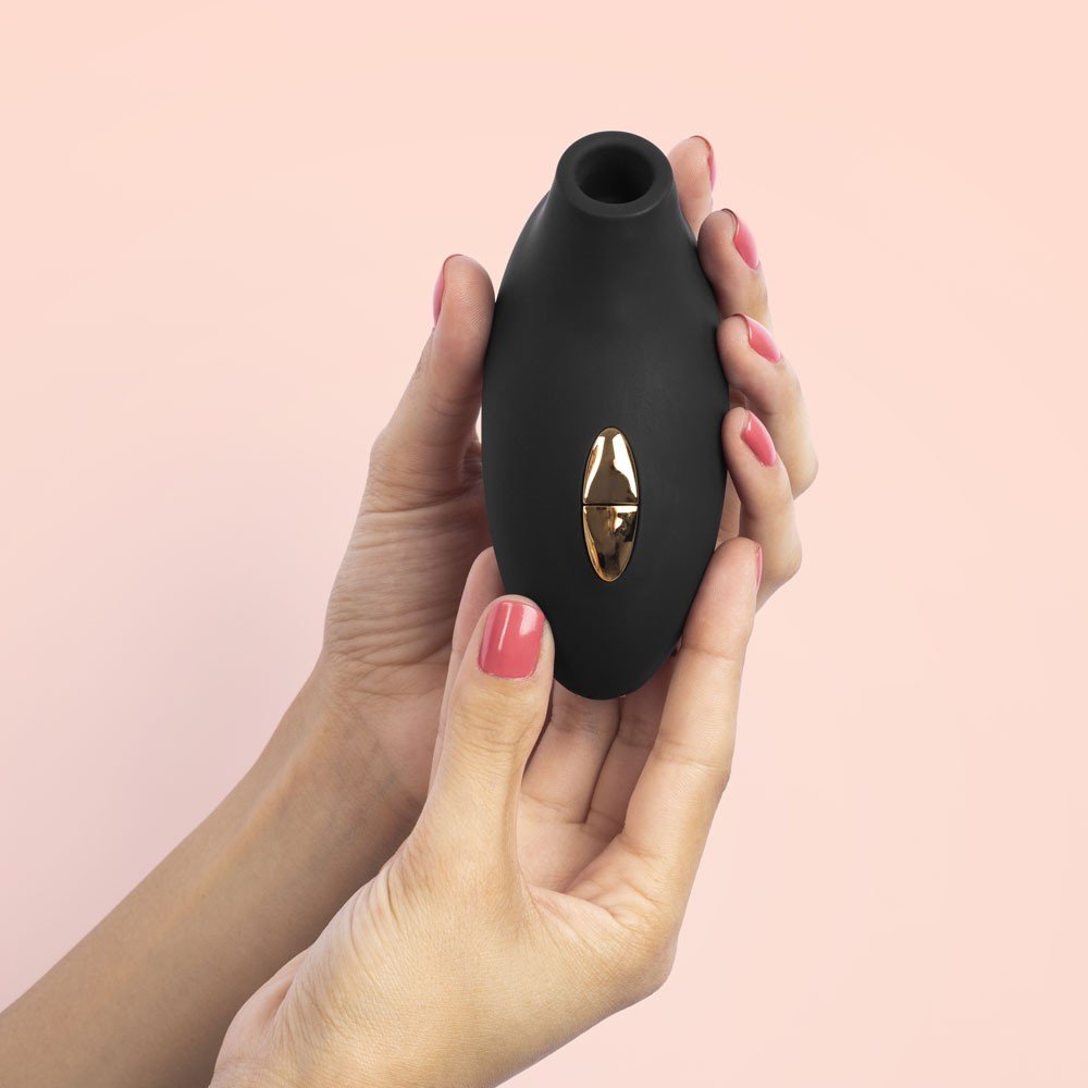Estimulador de Clit�ris em Silicone Recarreg�vel Dona Suck em m�os, mostrando o design ergon�mico, bot�es e textura aveludada.