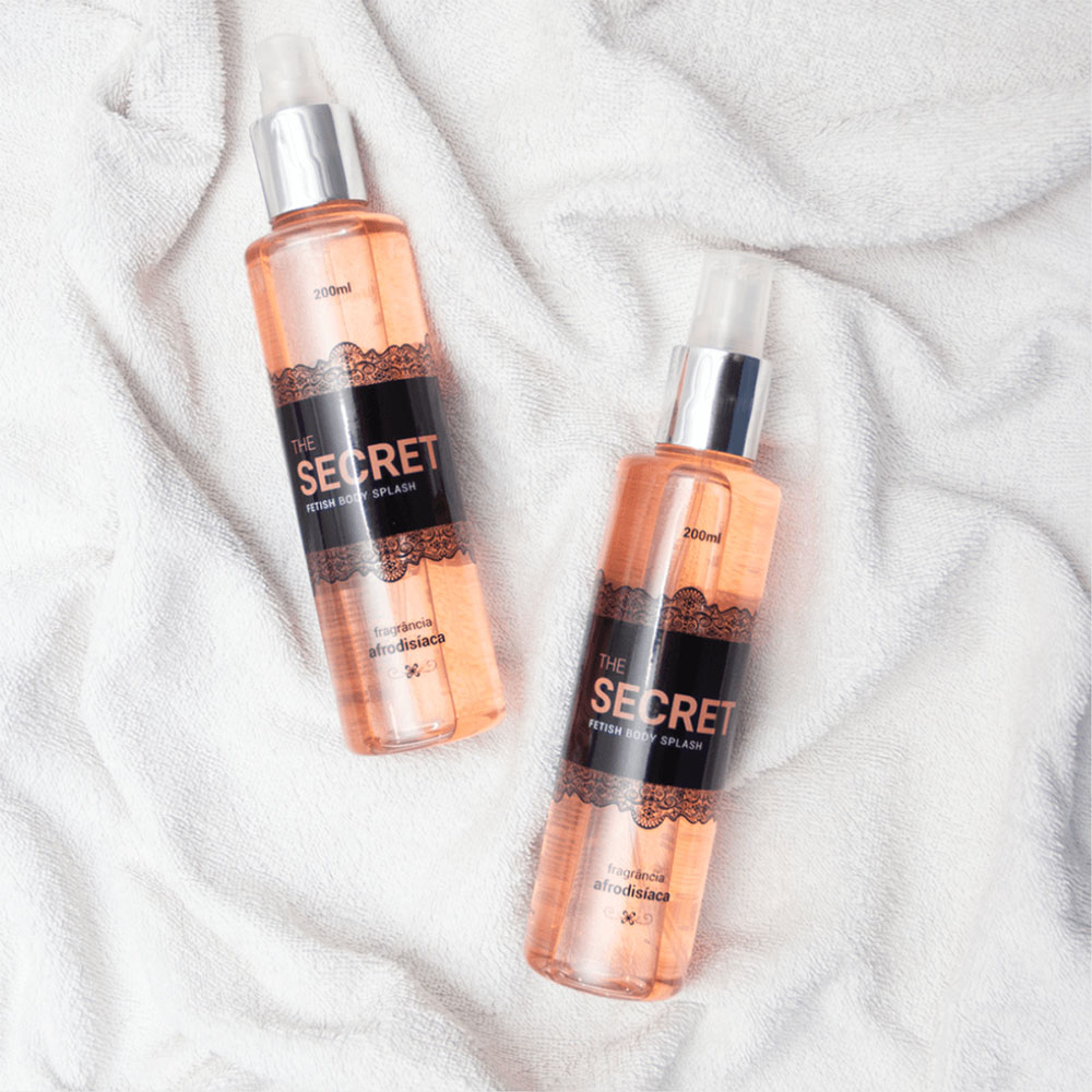 Duas unidades do Body Splash Fragr�ncia Afrodis�aca The Secret 200ml sobre uma toalha branca, mostrando a cor do l�quido e o design do frasco.