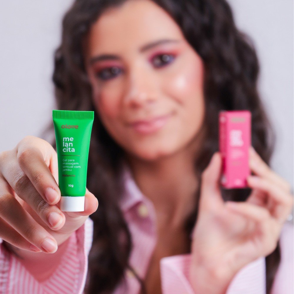 Gel Vibrador L�quido Beij�vel Amoracita Sabor Melancia sendo segurado por uma mulher, mostrando o frasco e a embalagem
