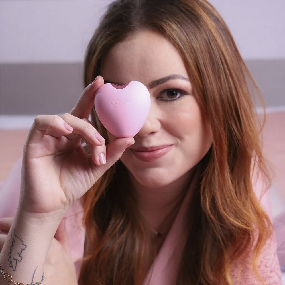 Vibrador para Clit�ris Recarreg�vel em Silicone Love Rosa, com modelo segurando o produto no rosto