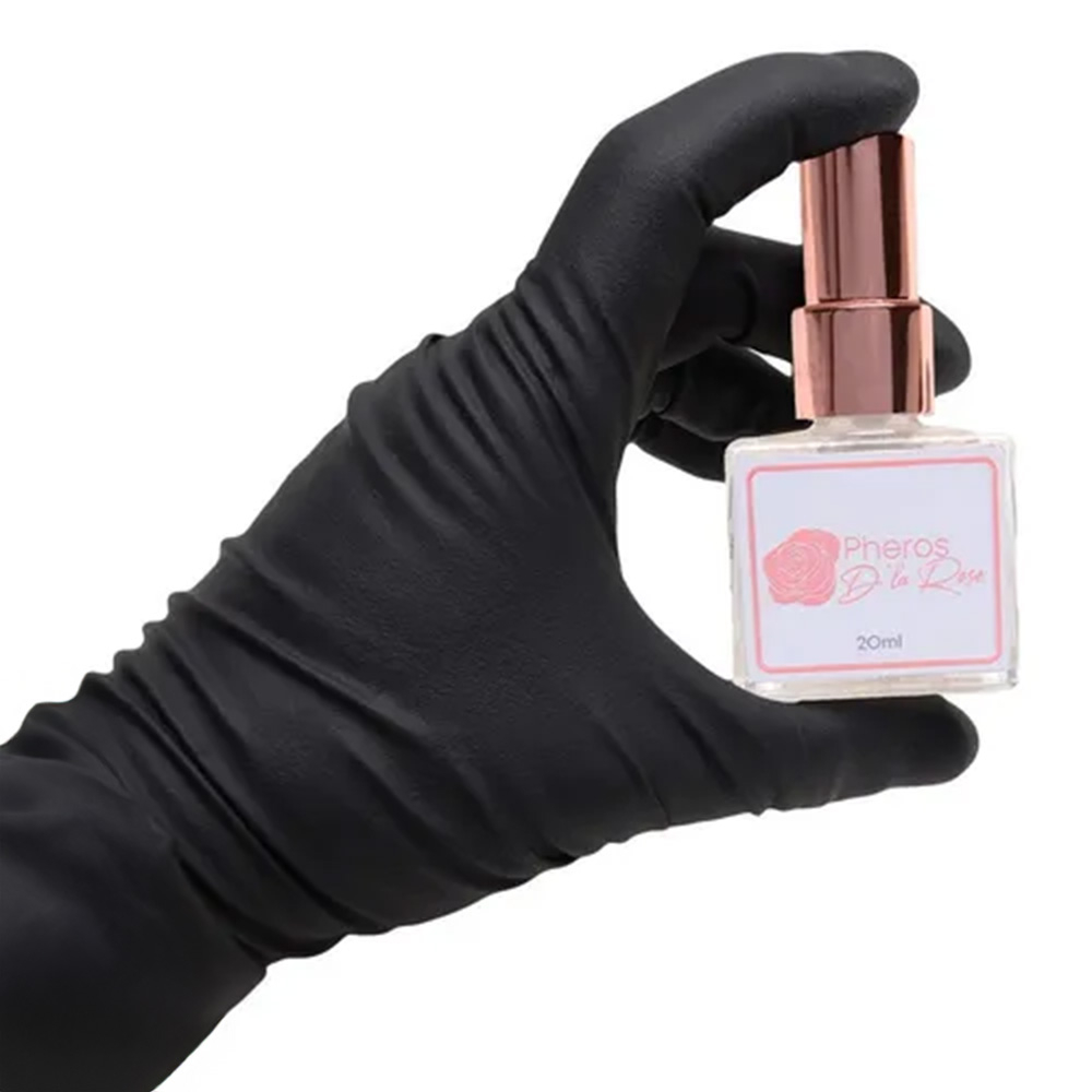 M�o enluvada segurando o Perfume Afrodis�aco Pheros D'la Rose 20ml, evidenciando o frasco e a embalagem em tamanho real