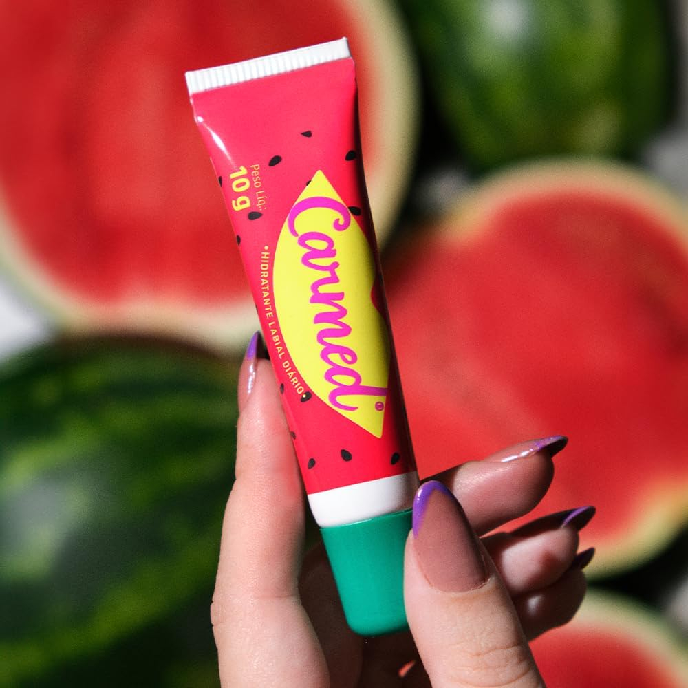 Hidratante Labial Carmed Incolor Aroma de Melancia 10g em destaque na m�o, com melancias cortadas ao fundo.