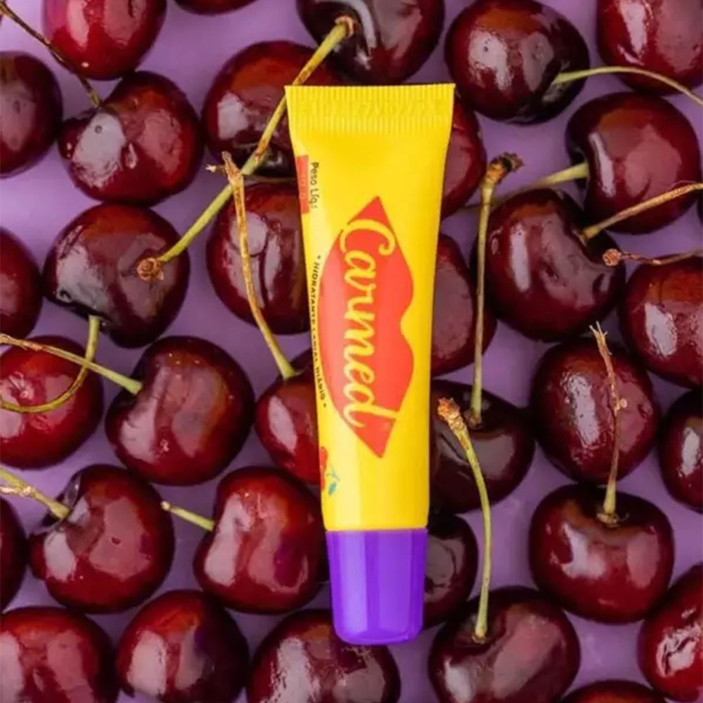 Carmed Incolor Aroma de Cereja 10g cercado por cerejas, mostrando a embalagem amarela com detalhes em roxo